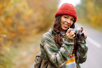 A beautiful young woman is photographed with a retro camera. Rest, relaxation, travel, lifestyle concept.