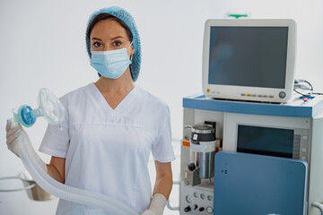 Fototapeta na wymiar Focused doctor anesthesiologist holding breathing mask for anesthesia standing in operation room 
