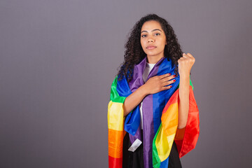 Young black Brazilian woman, with clenched fist, militancy with LGBT flag, diversity, fight against...