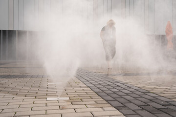 silhouette of a person passing through the water curtain cooling the air on a hot summer day in Prague