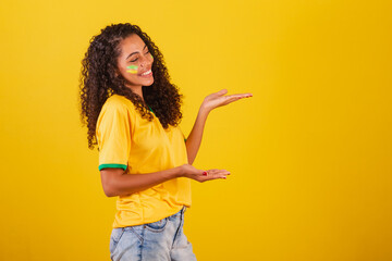 Young black Brazilian woman, soccer fan. presenting with hands to the right, publicity photo