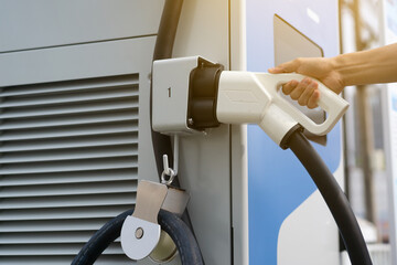 The male plugs the power cable in the electric car to charge.