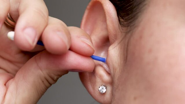girl use cotton ear swab stick for cleaning.4k real time isolated woman face part detail.daily hygiene concept product.earbud approaching from woman ear.wrong use danger stop risk of removing wax.