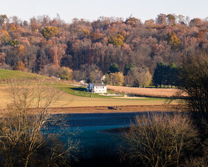 Fototapeta premium Amish school nestled in a wooded valley with farm fields in autumn in Holmes County, Ohio, USA