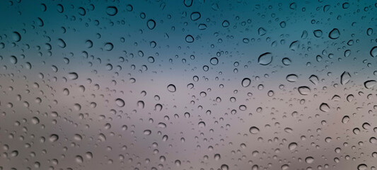 Raindrops on glass. A drop of water rolls down the glass. Macro photography of a raindrop. water condensate. Rain texture. The concept of sadness. Wet background. Glare of rain. Sparkling water drop.