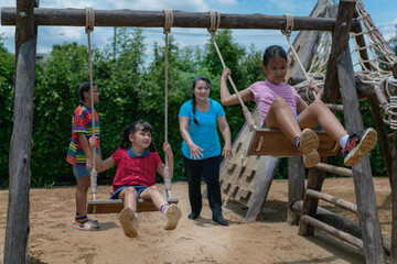 young women playing with swing . Teenagers having friends fun together while talking and swinging , Asian cute girl is having fun on a swing playing with her friends. in the playground