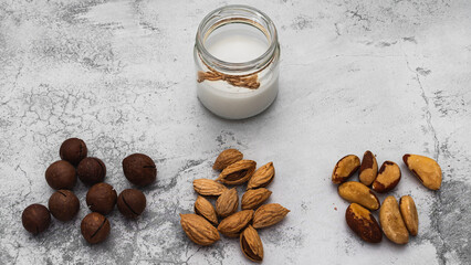 World Vegan Day concept. Nut milk in glass jar with almond, macadamia, brazil nuts. Homemade...