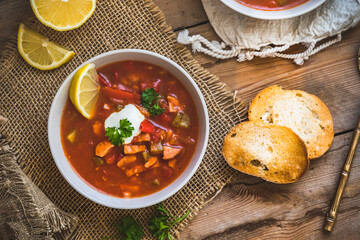 Bowl with Solyanka on, a spicy and sour soup of Russian origin, on wooden background. Soljanka is...