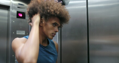 African man examining himself in front of elevator mirror © Marco