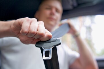 close up photo of hand and seat belt. Driving safety concept. Young man is fastening seat belt in the car