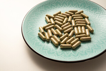 green plate with handful of kratom pills laying randomly, selective focus