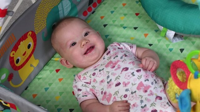 Adorable little newborn caucasian baby smiling and cooing on the playmat