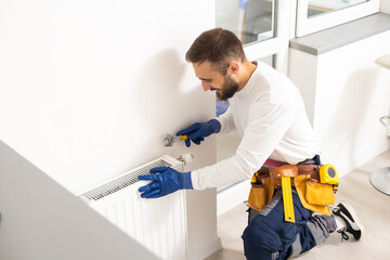 Repair heating radiator close-up. man repairing radiator with wrench. Removing air from the radiator