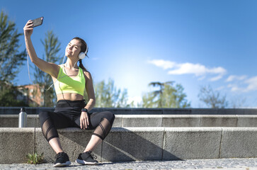 Fototapeta na wymiar happy woman taking selfie in a park with sportswear after running and headphones