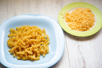 Raw curly pasta on a plate and grated cheese. Preparation for making pasta.