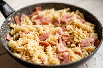 Pasta with bacon, sausage in a pan with a creamy sauce.