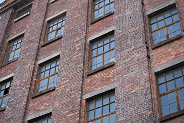 Fototapeta na wymiar Red brick wall of an abandoned factory with windows.