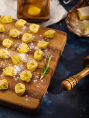 Raw homemade handmade dumplings on a floured cutting board on a blue marble background. Recipes for cooking dishes with minced meat. Family traditions. Home kitchen.