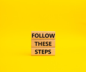 Follow these steps symbol. Wooden blocks with words Follow these steps. Beautiful yellow background. Business and Follow these steps concept. Copy space.