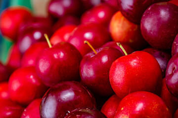 cherries in a bowl. cherries in the foreground. group of red fruits. selling tropical fruits in a latin american market place. cherries for sale.