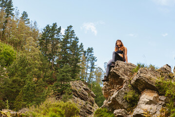 Hiker woman sitting on a rock taking a break while hiking in the mountains. weekend outdoor...