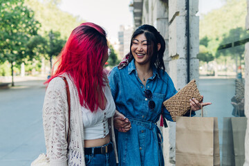 Two young happy Asian female friends looking at the window with shopping bags. Two women shopping.