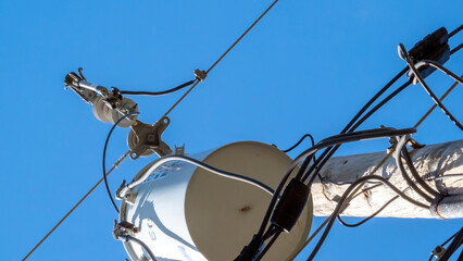 Electric transformer on utility pole, looking up from below, with blue sky in background