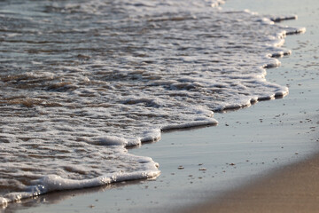 Widok na plażę z bałwanami fal morskich i bryzgami wody.