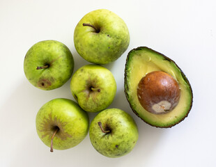 green apples and an avocado on white
