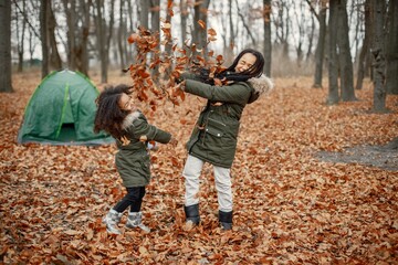 Two little black sisters playing near tent camping in the autumn forest