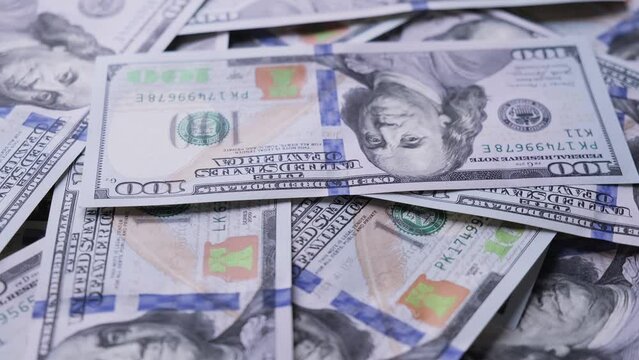 Man counting american one hundred dollar paper money at rotating table. Cash money banknotes. Finance and investment concept. Pile of american dollars. Close-up in 4K, UHD