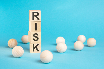 pyramid of wooden cubes with the word RISK and wooden balls on a blue background