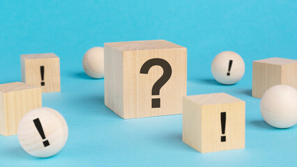 wooden toy cube with a question marks viewed high angle on a blue background with wooden balls and...