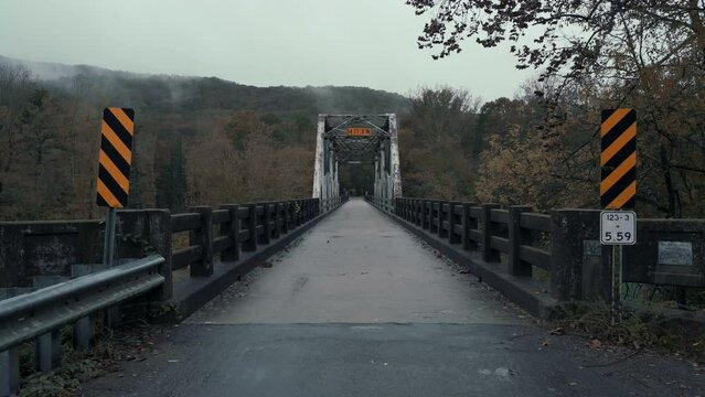 Dark and cold misty wet wether creates fog and misty conditions behind a rural countryside Arkansas bridge