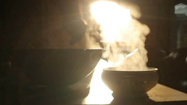 Cooking in a cauldron on the fire outdoors. Pieces of meat, onions and carrots are fried in boiling water in a pan on the fire. Takeaway food. Steaming hot food in a cauldron