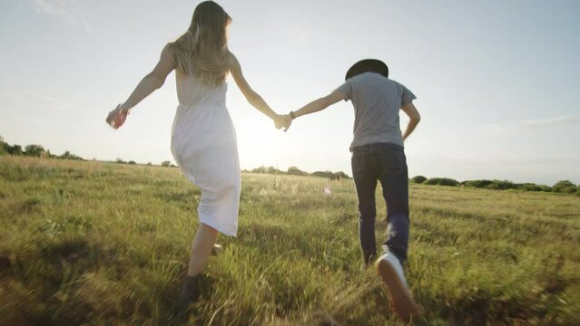 Cheerful beloved couple running and hugging on grassy field in countryside