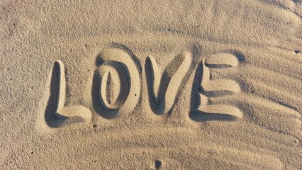 The word Love is written in the sand on the beach