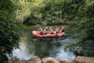 Group of tourists taking rafting tour on the Cetina river, listening to the information from the instructor in the dinghy