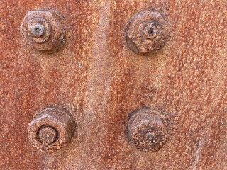 Rusted screws and rivets on a rusty metal plate
