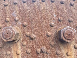 Rusted screws and rivets on a rusty metal plate