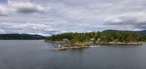 Treed Island with Homes, boats and docks, nearby smaller island with lighthouse. Summer Season. Gulf Islands near Vancouver Island, British Columbia, Canada. Canadian Landscape.