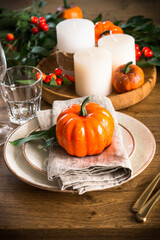 Autumn table setting with plate, pumpkin and candles at wooden table. Thanksgiving food concept.