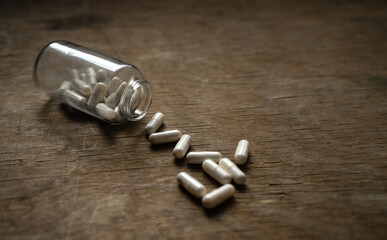 A bottle of pills scattered on a wooden table. Overdose with medications. Narcotic pills.