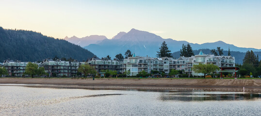 Obraz premium Vacation Homes by the lake and sandy beach. Sunny Summer Morning Sunrise Sky. Harrison Hot Springs, British Columbia, Canada.