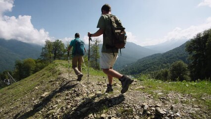 Senior students of geography are moving along mountain range in mountains of Caucasus. Return to base from training practice in alpine forest. Summer sports outdoor recreation