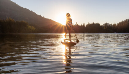 Adventurous Woman Paddling on a Paddle Board in a peaceful lake. Sunny Sunset. Hicks Lake,...