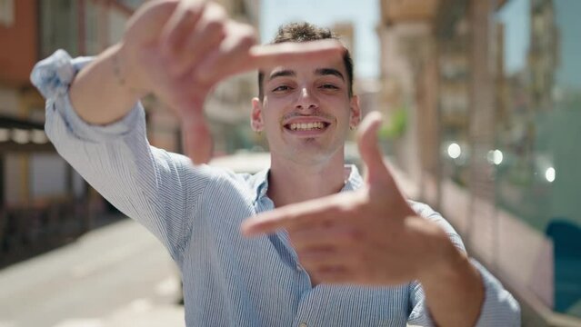 Young hispanic man smiling confident doing photo gesture with hands at street