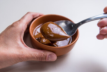 hands introducing a spoon into jam, close up