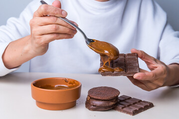 woman's hands putting dulce de leche on a chocolate, not suitable for diabetics.