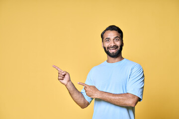 Happy excited indian man looking at camera pointing aside with fingers hand gesture indicating...
